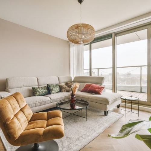Table with chairs and flowers located near lounge area and kitchen in spacious room of contemporary apartment